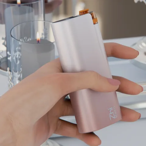 Hand holding the rose-gold Zhithera D1 waterless diffuser in front of a lit glass candle