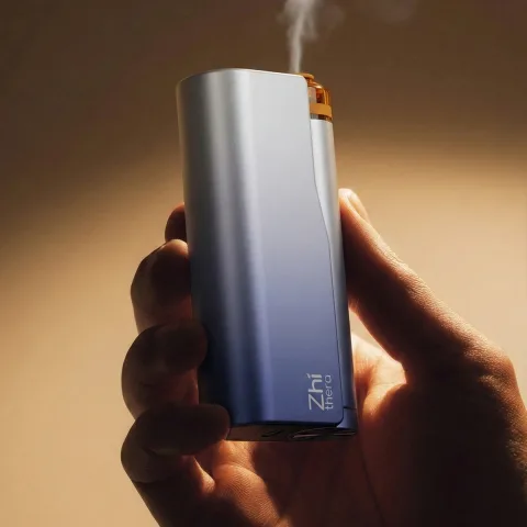 Hand holding the Zhithera D1 waterless nebulizing diffuser as a thin mist rises from the top