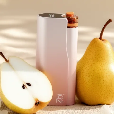 Blush-pink Zhithera D1 waterless diffuser between two halved pears on a linen surface