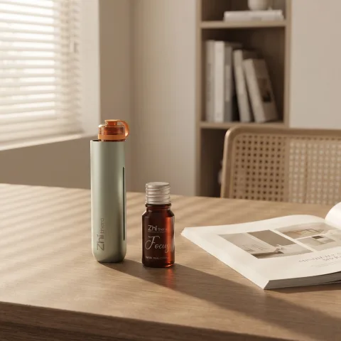 Sage Zhithera D1 Mini diffuser on a desk beside a 10 ml essential oil labeled "Focus"