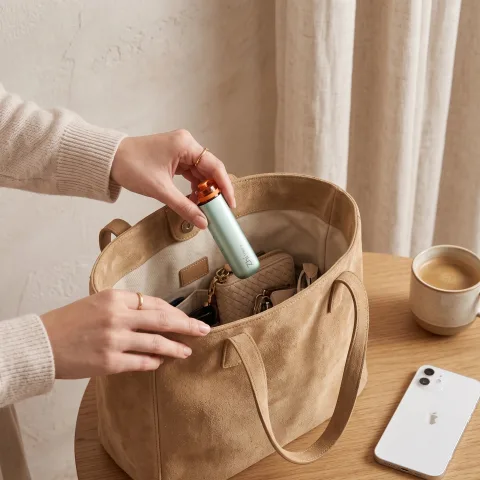 Hands placing the Zhithera D1 Mini portable diffuser into a suede tote bag