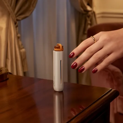 Hand reaching for a white Zhithera D1 Mini waterless diffuser on a polished side table