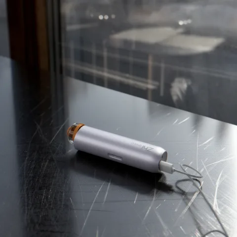 Silver Zhithera D1 Mini portable diffuser charging on a dark wooden table