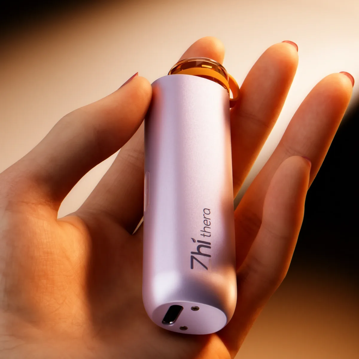 Hand holding a lilac Zhithera D1 Mini portable diffuser, close-up of the logo